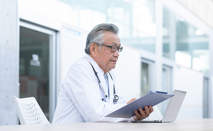 白衣を着た医師がバインダーの資料を確認している様子