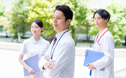 3人の医療従事者が屋外で一方を見つめている様子